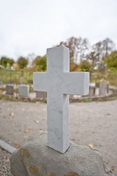 A gravestone with a cross in a graveyard