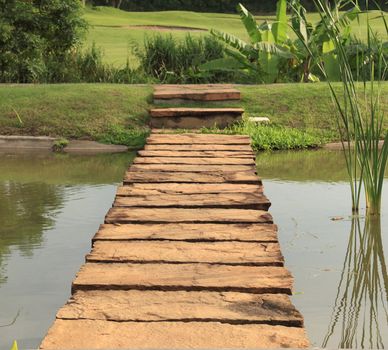 Stone path across pond lead to green garden