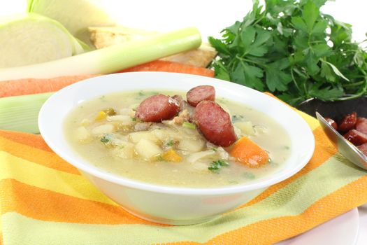 white cabbage soup with vegetables and fried sausage