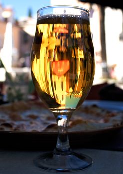 A glass of beer reflecting an old construction of Montenegro Rose village