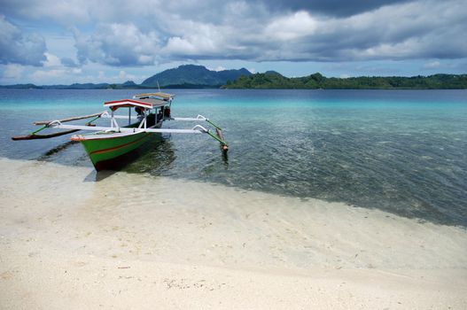 Indonesian boat anchored on the white beach