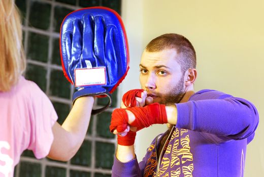 young adult man boxing in gym with his trainer