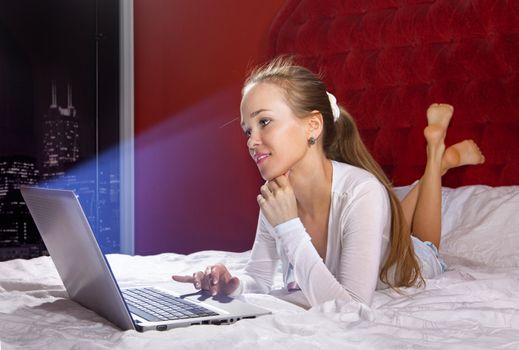 young happy woman on the bed with laptop