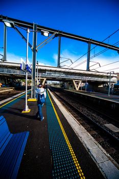 SYDNEY, AUSTRALIA - CIRCA JULY 2012: Unidentified woman stands and waits for the morning train at a platform with safety dots on clear sunny blue sky day circa July 2012 in Sydney, Australia.