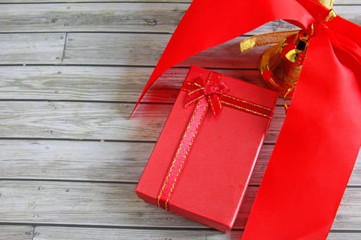 Gift box and red ribbon over wooden background 