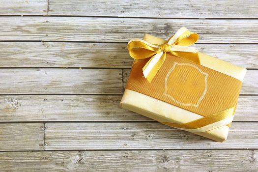 Gold present box on wooden background 