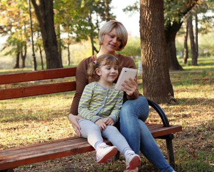 mother and daughter with tablet in park