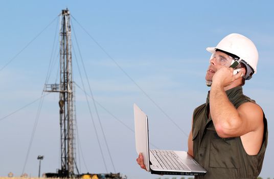 oil worker with laptop and rig