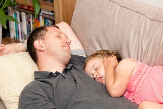 Father and daughter napping on the sofa.