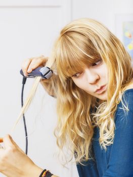 An image of a beautiful teenage girl smooting her hair