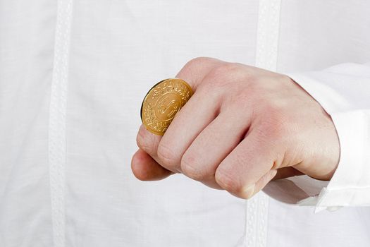 Close-up photograph of a golden coin between a man's fingers.