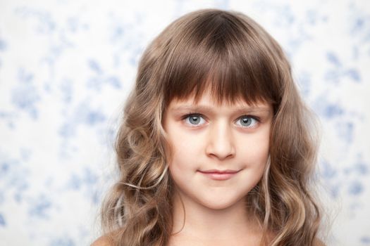 Portrait of sincere cheerful tender young blond girl child with grey eyes and wavy long hair looking at camera