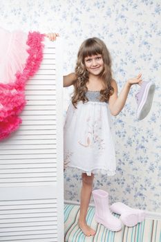 Young blond girl child with long wave hair looks out the folding screen when change of clothes