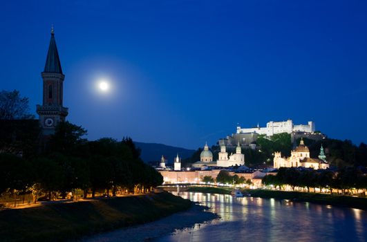 Twilight in Salzburg, view on church, river banks and fortress on the hill