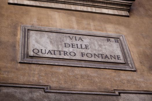 Marble street sign via Quattro fontane (four fontauns) on the painted stone wall in Rome, Italy