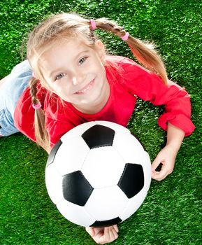 little girl with soccer ball  on a green lawn