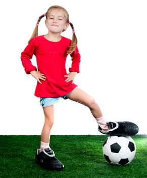 little girl with soccer ball in boots on a green lawn