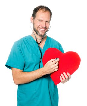A male doctor examining a red heart shaped pillow with a stethoscope against white background