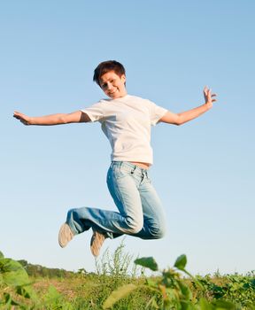 pretty young woman jumping on green grass