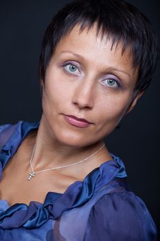 Close-up portrait of elegant stylish young romantic brunette woman in blue blouse on black background