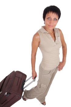 Smiling young tourist haircut woman dressed buff trouser suit stands with brown traveling suitcase isolated