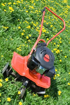 Hand tractor plough from front side on the flowering dandelion field Vertical