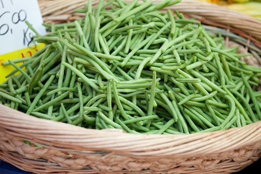 Fresh pods of vegetable green string beans macro in woven basket close-up at the table