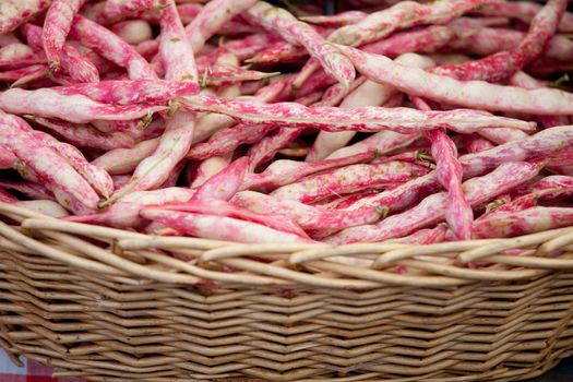 Fresh pods of vegetable speckled red string beans macro in woven basket close-up at the table