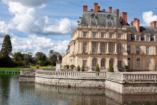 Medieval landmark royal hunting castle Fontainbleau near Paris in France and lake with white swans