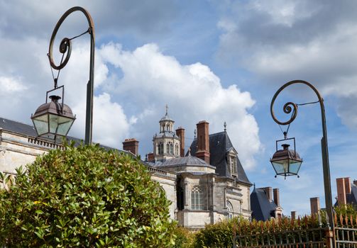 Medieval landmark royal hunting castle Fontainbleau near Paris in France and garden on the cloudy sky background