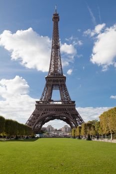 European national landmark Eiffel tower through leaves of park trees in spring in city Paris France on the blue sky background