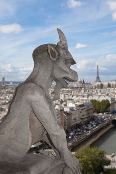 Gothic gargoyle Statue on cloudy sky background and top view from cathedral Notre Dame on streets, center, downtown, tower Eiffel in city Paris France in summer