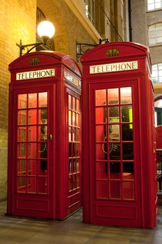 Traditional London symbol red public phone boxes at illuminated evening street. Great Britain