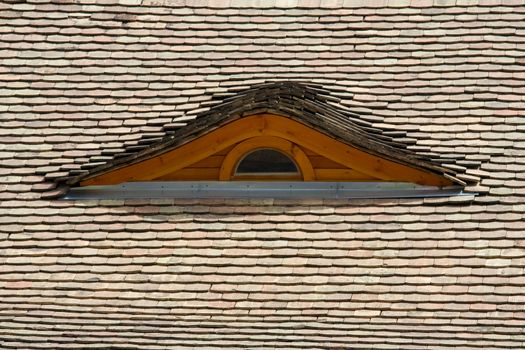 Attic wooden window on the tilled roof