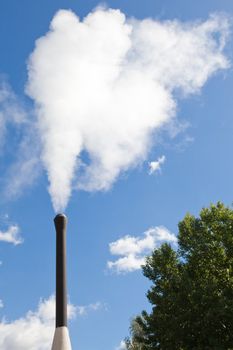 Industrial pipe polluting white steam on the blue sky background