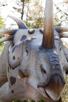 Head of reptile dinosaur styracosaurus albertensis Ceratopsn with bone horns and beak from late Cretaceous period on green leaves and sky background