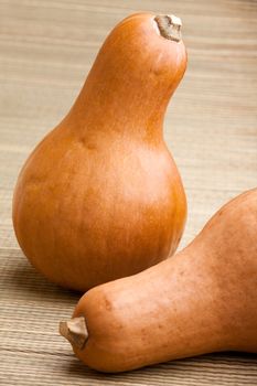 Group of ripe orange gourds on rural straw woven surface and stripy background