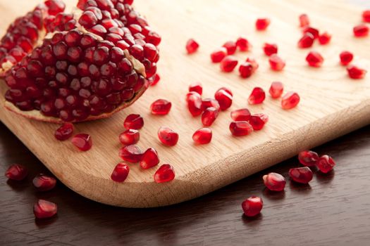 Pomegranate slices and seeds on wooden background