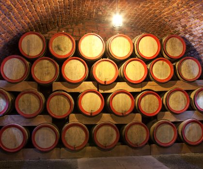 Wooden wine barrels are stored in winery cellar close-up