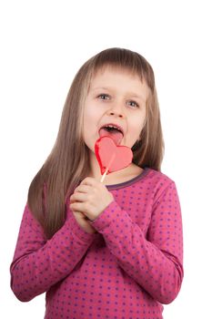 Portrait of little cute happy girl 7-8 years old licking red sweet lollipop in the shape of heart isolated