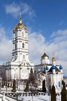 Belfry, dome and church of ancient sacred Christian Pochaev Monastery of Holy Dormition on blue cloudy sky background. Western Ukraine, Ternopol region, 16th century