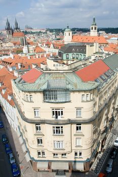 Top view cityscape on facades, red tiled mansard roofs, old Prague streets and district, Gothic cathedrals on blue sky background