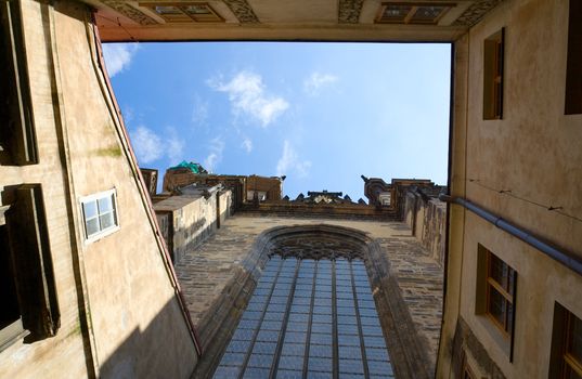 View on blue cloudy sky from inner encloused court of stone catholic gothic church of Virgin Mary Before Tyn with round-headed glass window in Prague Czech Republic