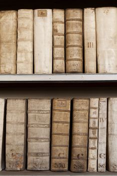 Hard covers of rust moldy ancient books monuscripts on wooden shelves in bookcase