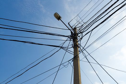 Lamp pole and tangled electric wires on the blue sky background. Horizontal