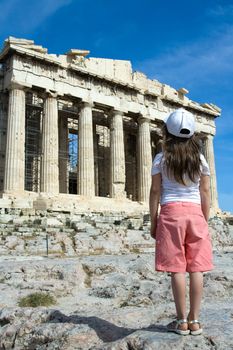 Child in front of Facade of ancient temple Parthenon in Acropolis Athens Greece on the blue sky background