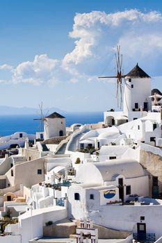 Old-style white traditional windmills in terraced village Oia of Cyclades island Santorini Greece on the blue Aegean Sea and sky background