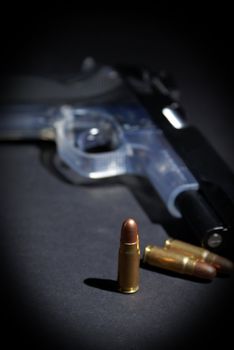 A handgun and selective focus on the upright bullet.