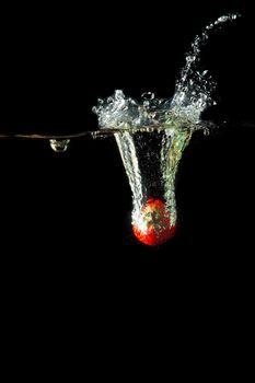 Colored red paprika in water splashes on black background