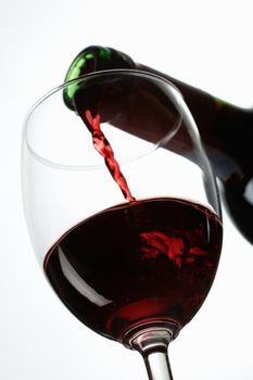 Red wine pour in a glass on white background